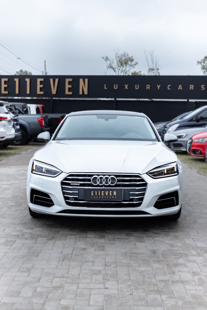Front view of a white Audi car parked at a luxury car dealership.