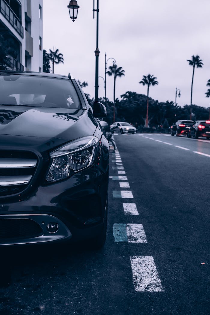 Parked car on a Rabat street with palm trees and evening lights creating an urban atmosphere.